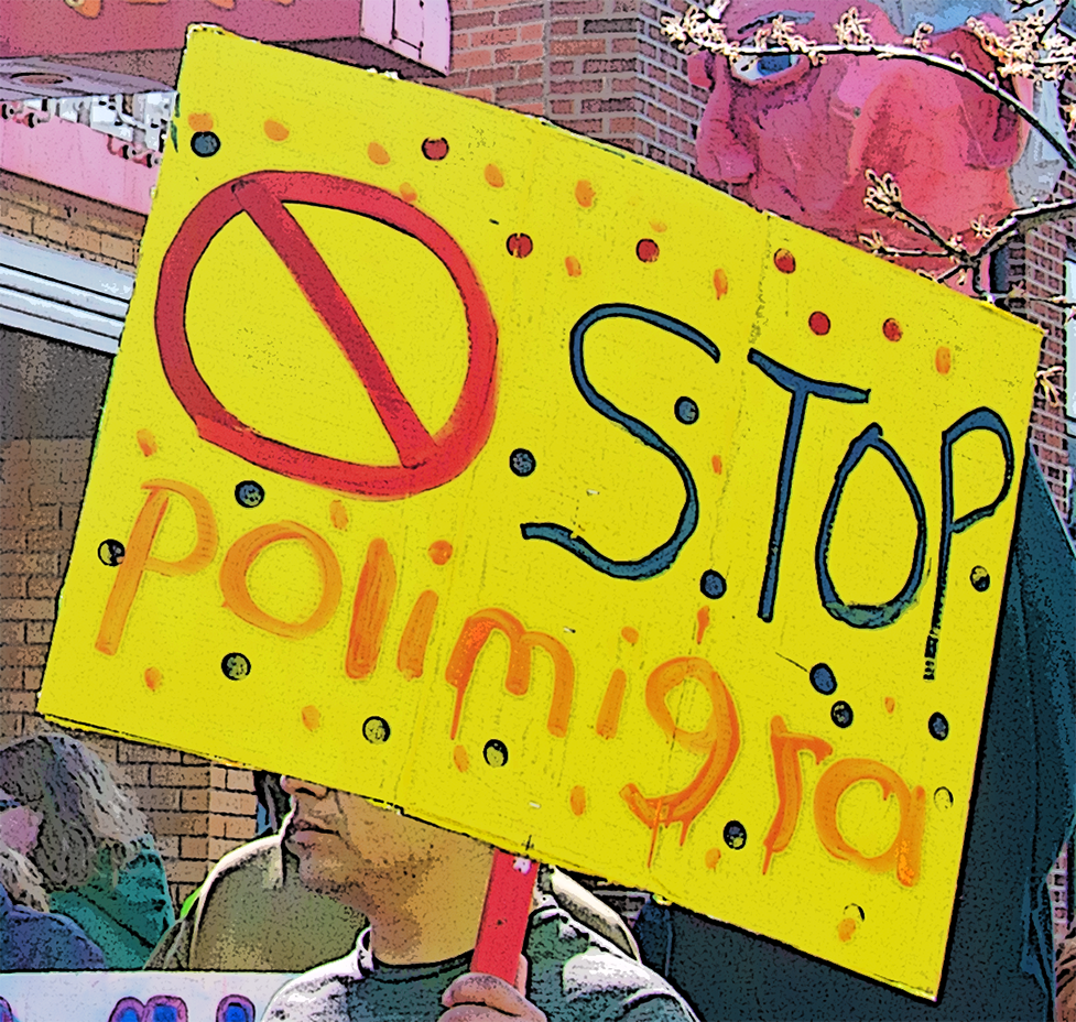 You see a poster with the words Stop Polimigra and at the top an eye from another poster both carried at a protest march in Springdale Arkansas on 31 March 2025